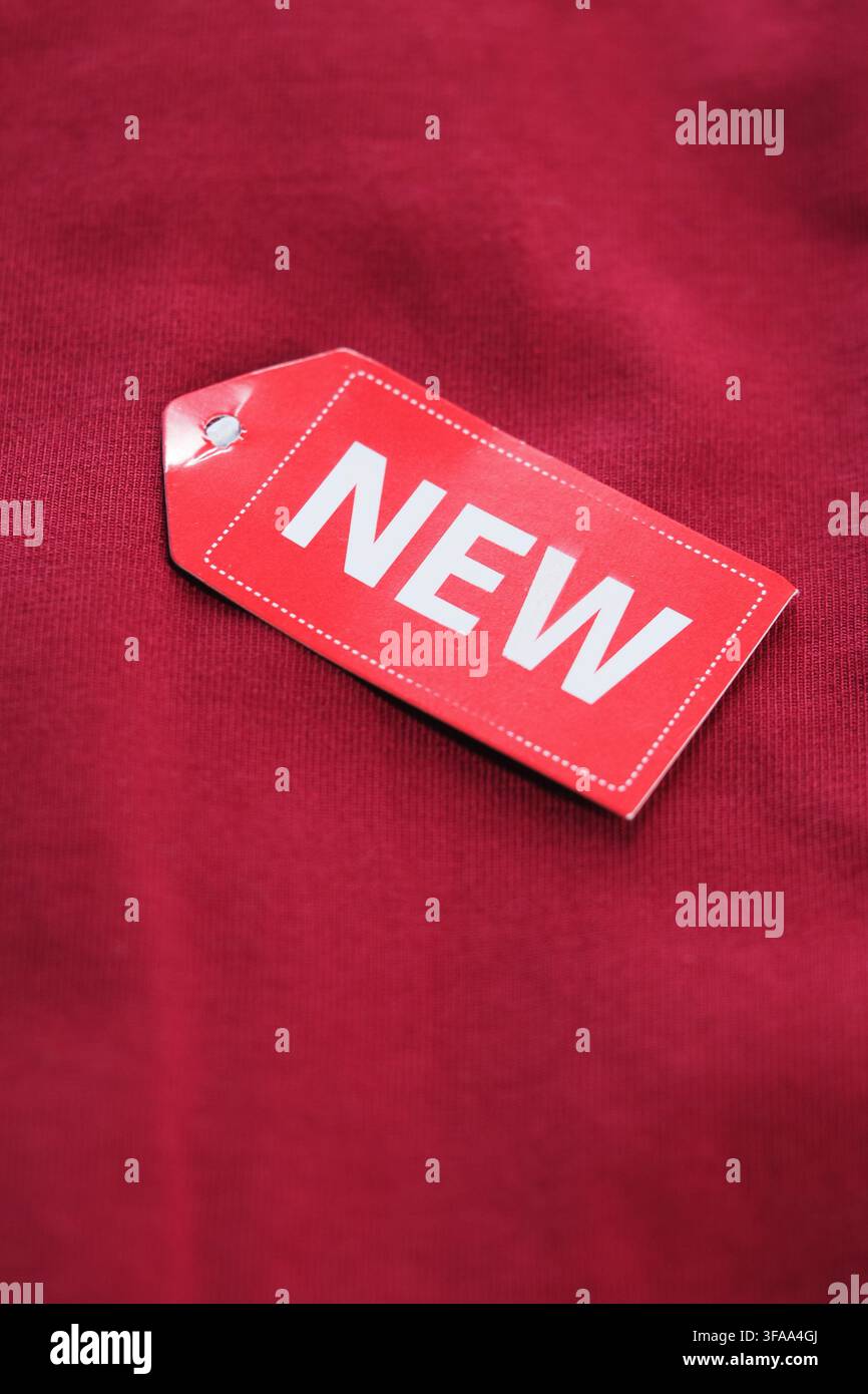 L'etichetta dell'abbigliamento mostra una nuova marca su un tessuto rosso Foto Stock