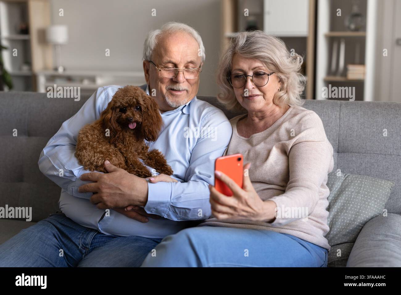 Coppia di anziani che fa una videochiamata su smartphone con un cane domestico Foto Stock