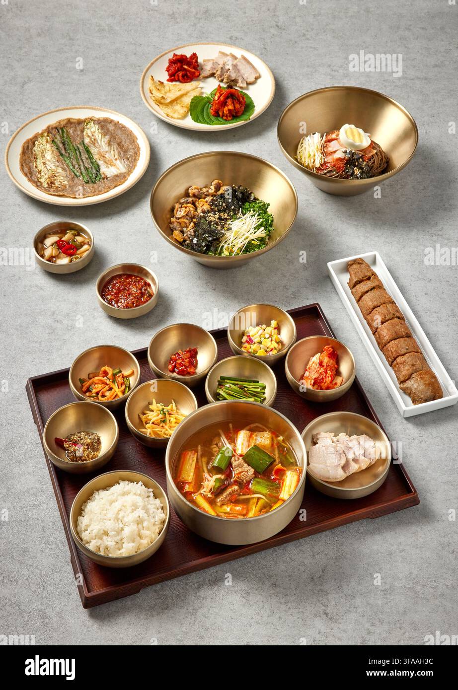 Pasto completo tradizionale coreano con stufato di pasta di fagioli neri Doenjang Jjigae, riso e assortiti piatti di accompagnamento Banchan in ciotole dorate su un vassoio di legno, Cor Foto Stock