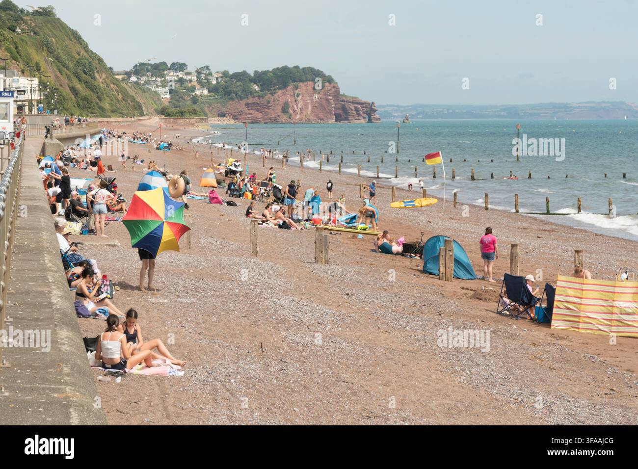 Persone che godono del sole estivo sulla spiaggia di Teignmouth nel Devon, Inghilterra, Regno Unito Foto Stock