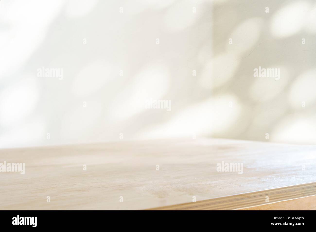 Sfondo ombra tavolo. Tavolo di legno e muro bianco vuoto con ombre di piante.. Foto Stock
