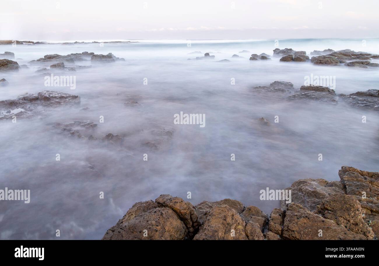 Immagine astratta d'atmosfera a lunga esposizione di onde che si infrangono su una costa rocciosa. Foto Stock