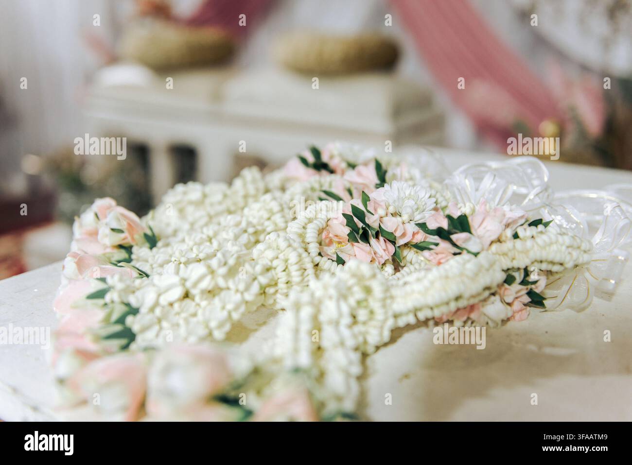 Primo piano di ghirlande floreali tradizionali tailandesi di gelsomino fresco (Phuang Malai) dettagliate con nastri bianchi e accenti rosa. Foto Stock