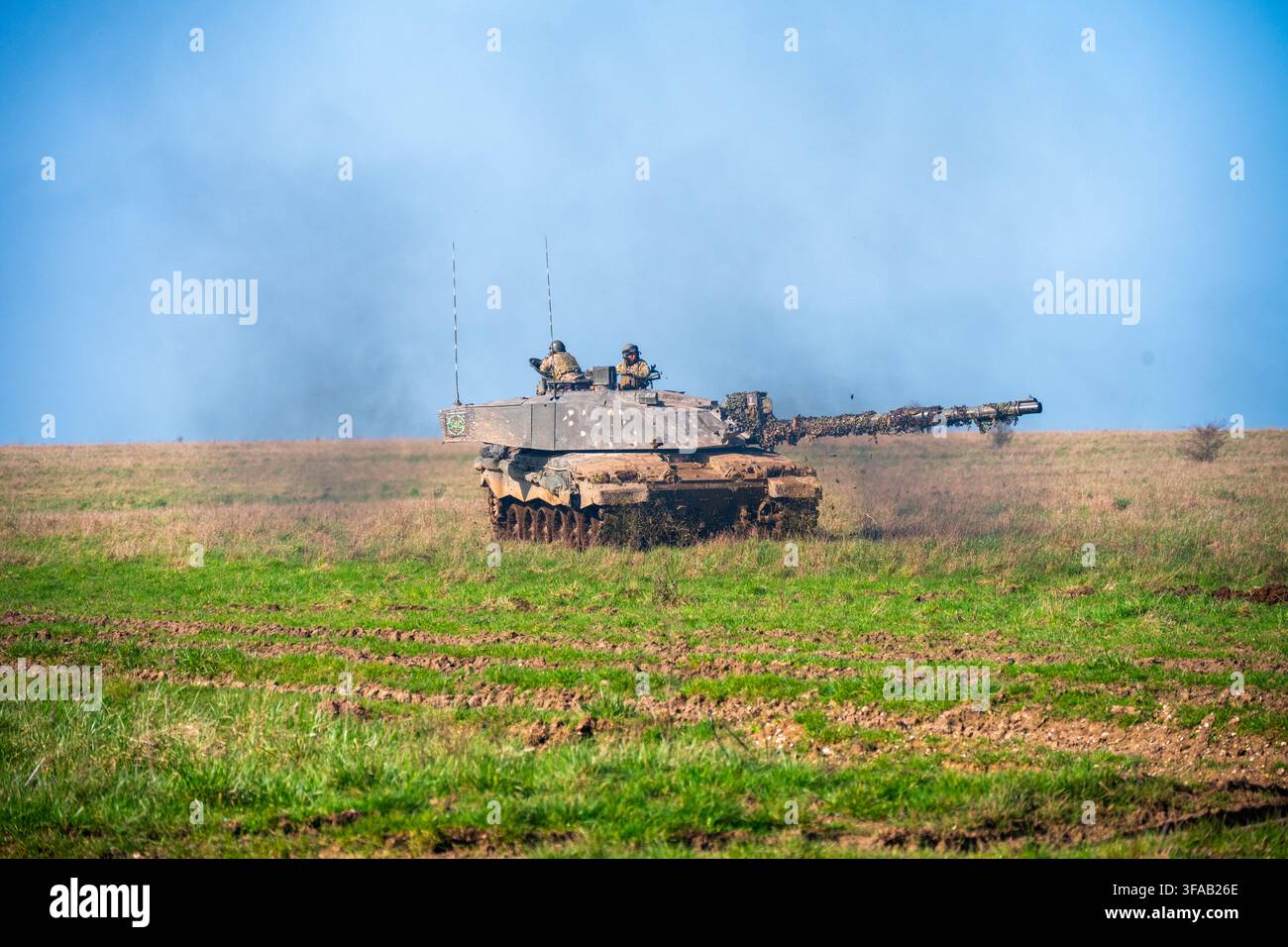 Vista di un carro armato principale Challenger 2 dell'esercito britannico che si muove sul terreno erboso della Salisbury Plain con i membri dell'equipaggio visibili nella torretta, Sali Foto Stock