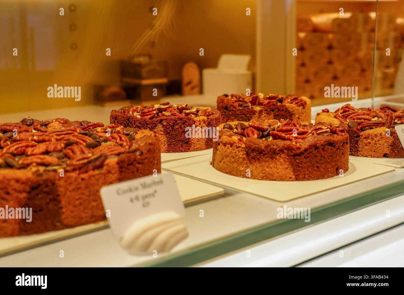 Biscotti con noci pecan e gocce di cioccolato appena sfornati in una vetrina di panetteria francese, che offre dessert di pasticceria gourmet in vendita a Parigi Foto Stock