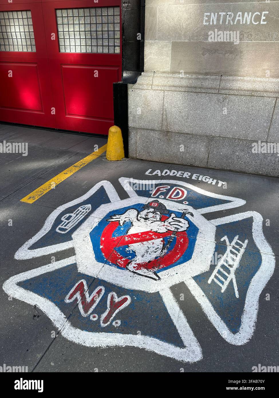 NEW YORK, NY - 12 FEBBRAIO 2024: Il logo di Ghostbusters dipinto sul marciapiede fuori da "Ladder Eight", la caserma dei vigili del fuoco del FDNY utilizzata come location cinematografica - Immagine stock catturata con smartphone