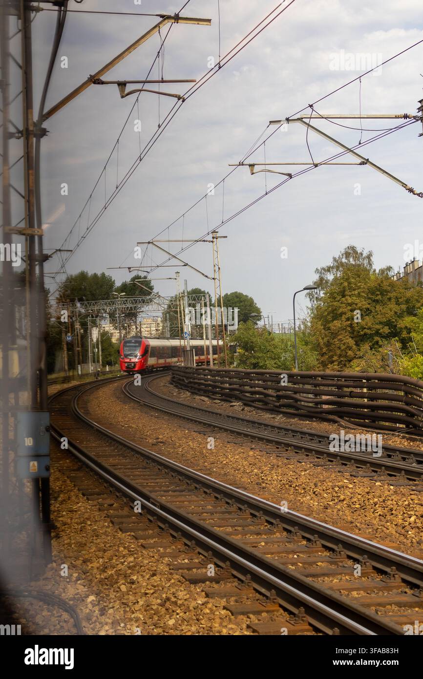 Binari ferroviari vuoti si estendono verso l'orizzonte sotto un cielo nuvoloso e cupo in una campagna tranquilla. Concetto di voglia di viaggiare, anticipazione dei viaggi ferroviari e jour Foto Stock