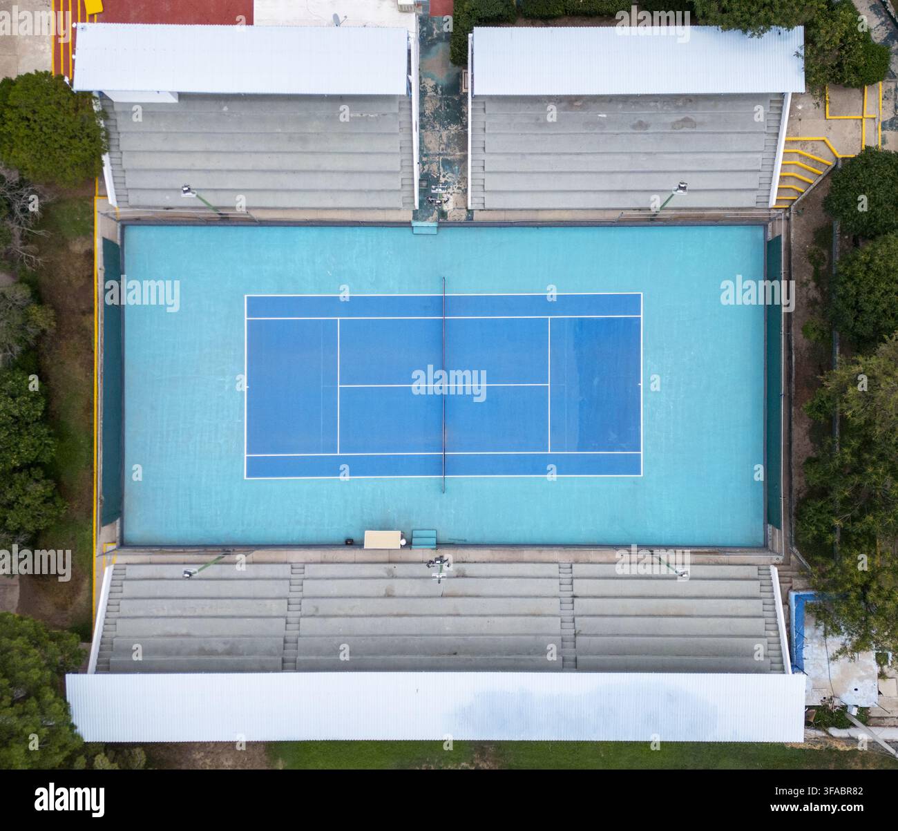 Vista aerea di un campo da tennis blu situato in una zona residenziale con sedute e alberi circostanti a Chihuahua, Chihuahua, Messico. Foto Stock