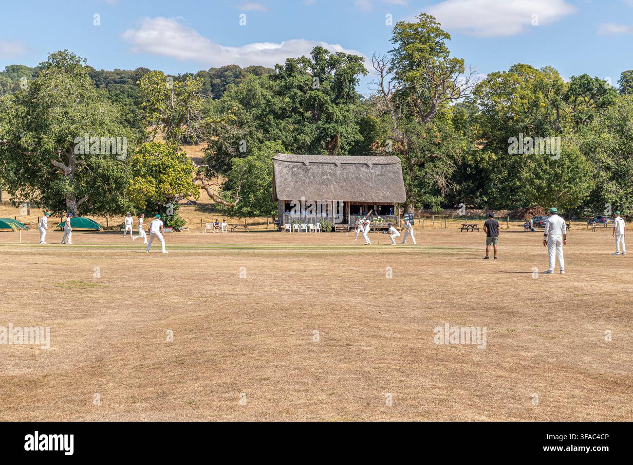 Una partita di cricket su un campo estremamente arido durante la siccità dell'agosto 2026 a Stanway, Gloucestershire, Inghilterra UK. Padiglione di J M Barrie. Foto Stock