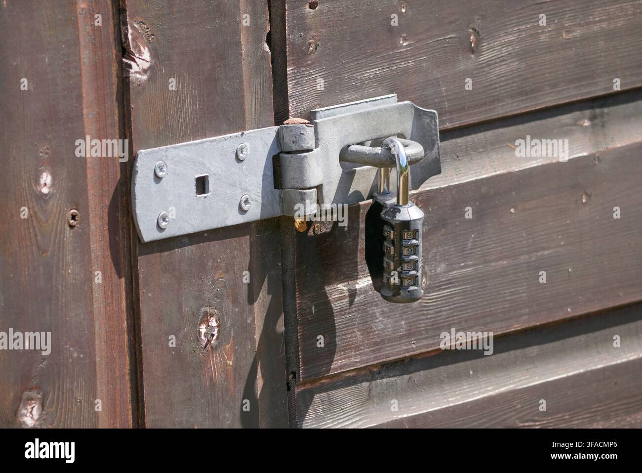 Serratura a combinazione su una porta di capannone, chiusa, argento, grigio, marrone, legno a doghe Foto Stock