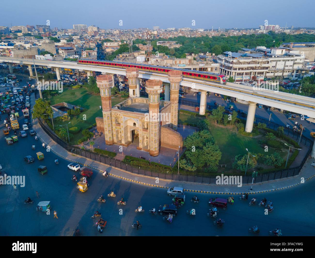 Vista aerea del monumentale storico Chauburji circondato dal traffico intenso e dal binario sopraelevato della linea metro Orange nella paesaggio urbano di Lahore, P Foto Stock