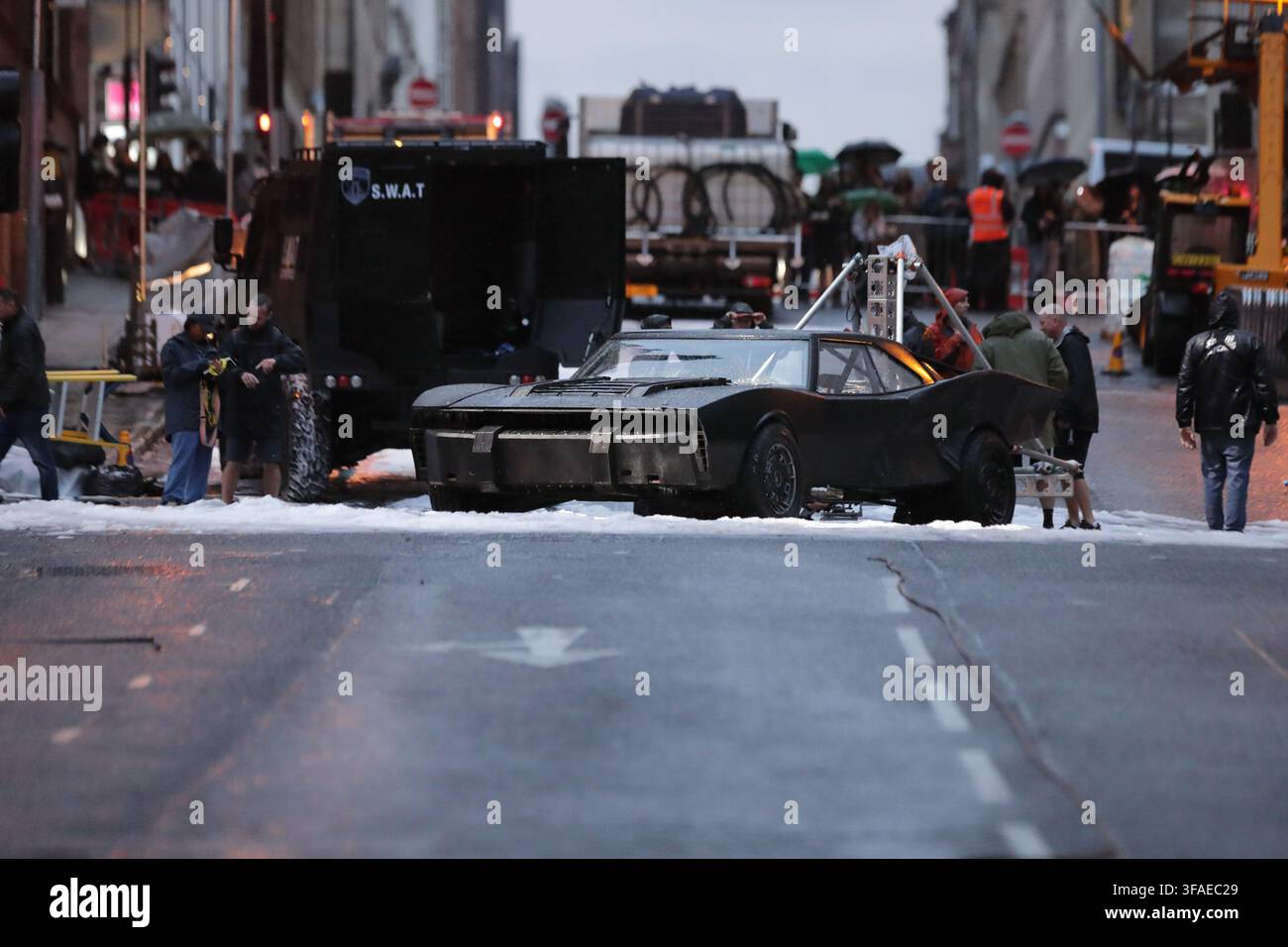 GLASGOW, UK. 19 agosto 2026. IL BATMAN: PARTE II PROPRIETÀ VEICOLO BATMOBILE preparata su un pezzo di neve artificiale su Bothwell Street prima delle riprese. Il veicolo è posizionato in una vista a tre quarti, con la griglia anteriore in netto fuoco e leggermente illuminata mentre la parte posteriore del telaio si allontana gradualmente fuori fuoco. L'asfalto bagnato conduce alla proprietà, che è affiancata da membri della troupe di produzione cinematografica su entrambi i lati, con un veicolo SWAT blindato che mostra un logo SWAT parzialmente sfocato visibile sullo sfondo a sinistra. Credit: Kyn Wai Chung/Alamy Live News Foto Stock