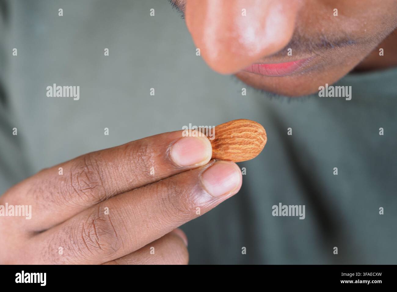 Un uomo tiene una mandorla mentre la esamina da vicino Foto Stock