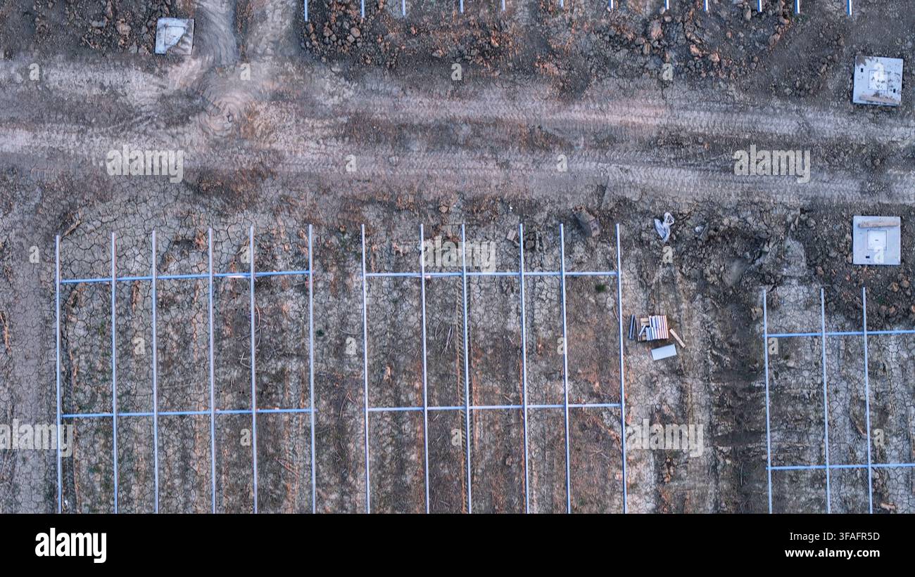 Cantiere di costruzione di una fattoria solare nella valle del Po: sviluppo e installazione di strutture di montaggio per pannelli fotovoltaici, preparazione del terreno ed energia rinnovabile futura Foto Stock