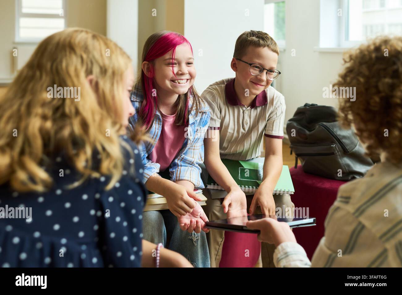 Scuola felici seduti in cerchio e conversano durante la lezione Foto Stock