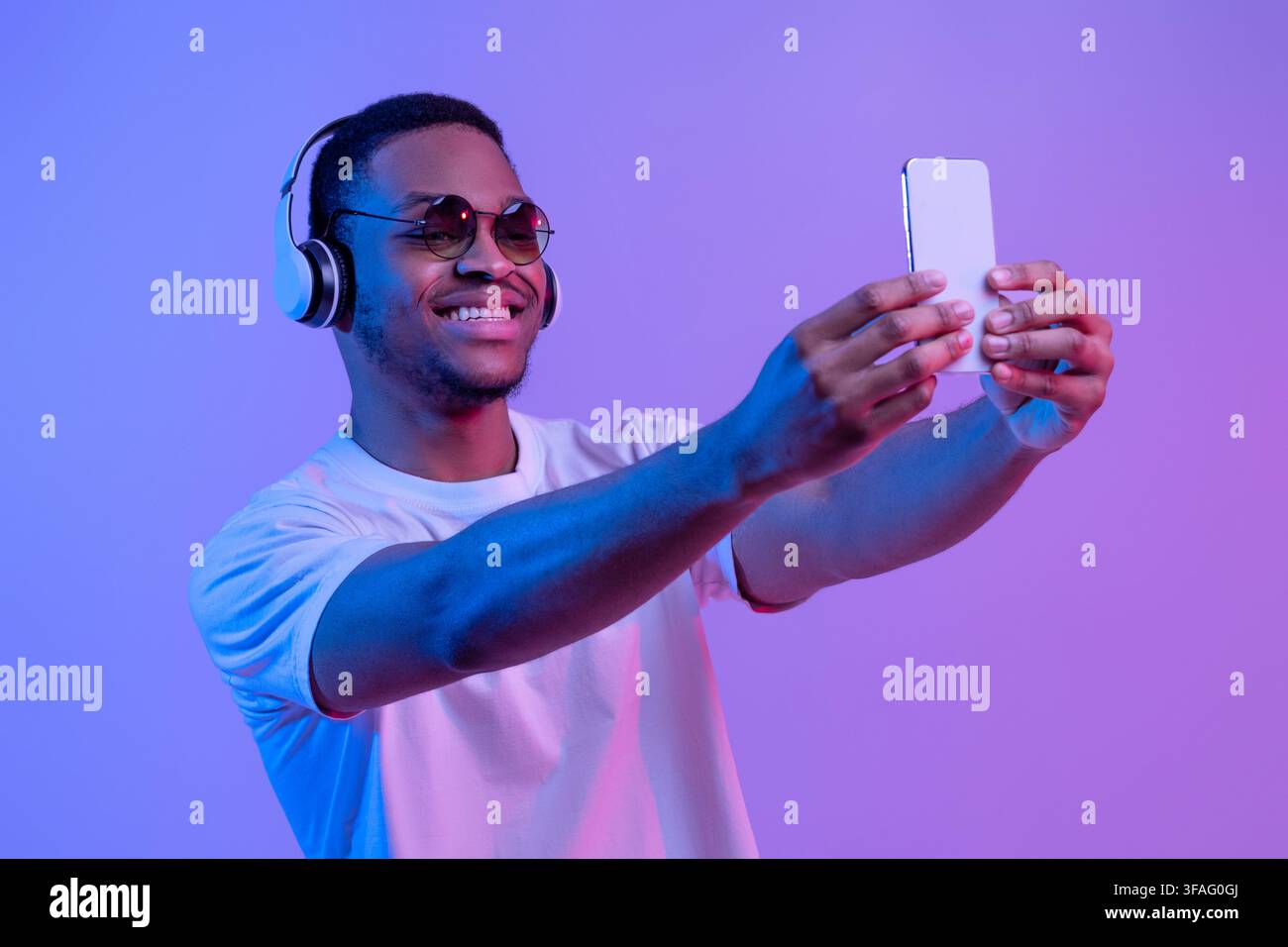 Bell'ragazzo nero in cuffie wireless e occhiali da sole che prendono Selfie Sullo smartphone Foto Stock