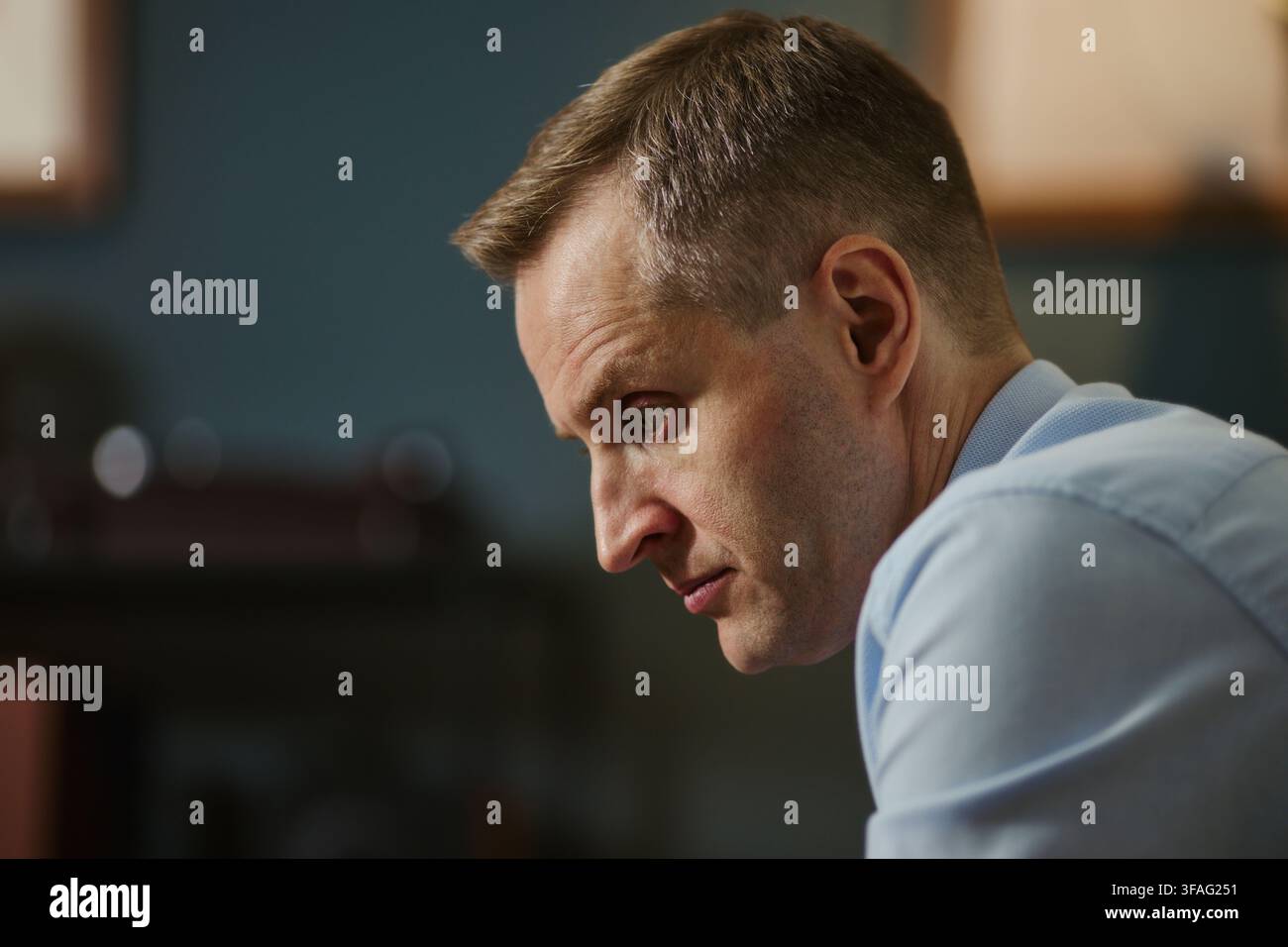 Uomo d'affari caucasico di mezza età che guarda verso il basso con espressione seria, rappresentante stress, esaurimento o concentrazione profonda. Ideale per campagne sulla salute mentale aziendale, primo piano Foto Stock