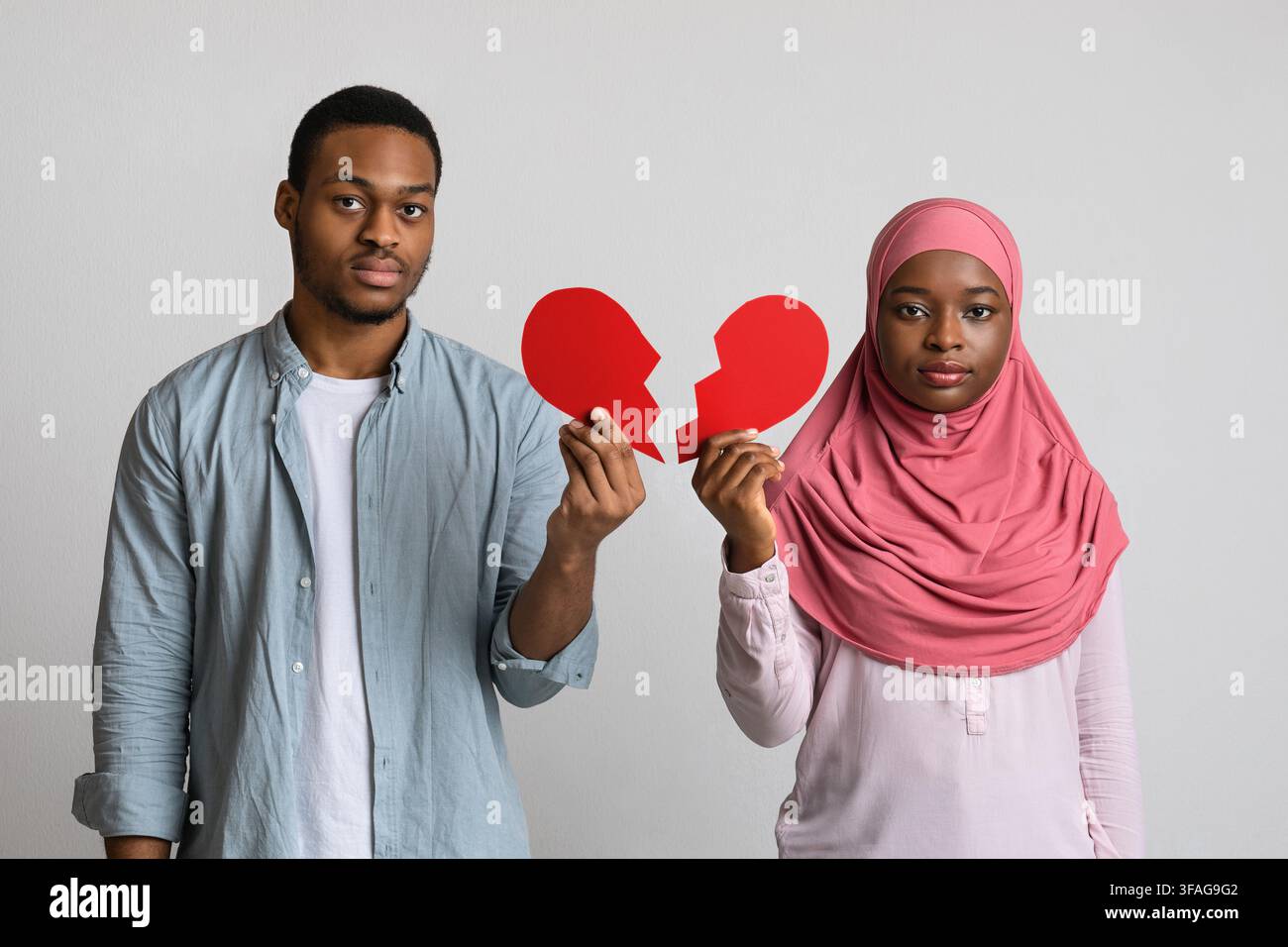 Uomo nero deluso e donna che tiene metà del cuore rotto Foto Stock