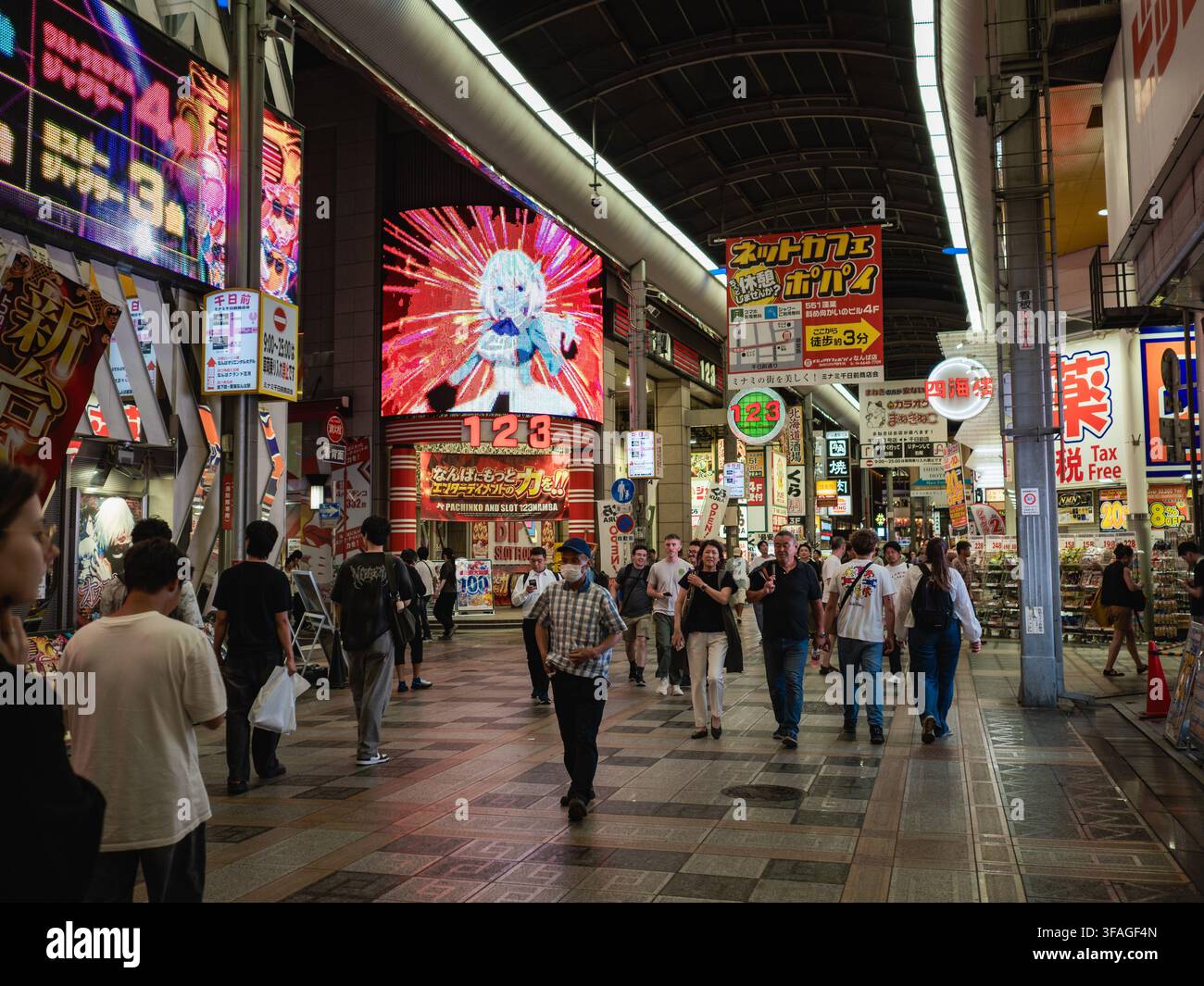 Acquistiatori che camminano attraverso il passaggio commerciale coperto Sennichimae con insegne al neon e schermi LED a Osaka, Giappone Foto Stock
