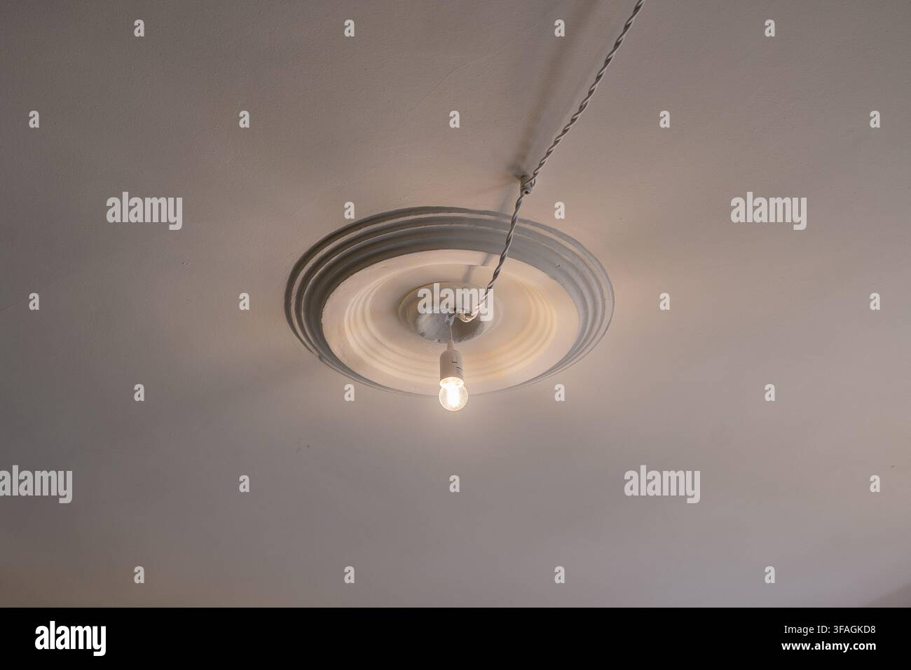 Apparecchio di illuminazione a soffitto illuminato in un ambiente interno con atmosfera neutra e materiali puliti, vista dall'alto per casi d'uso nella progettazione di interni e nella decorazione domestica Foto Stock
