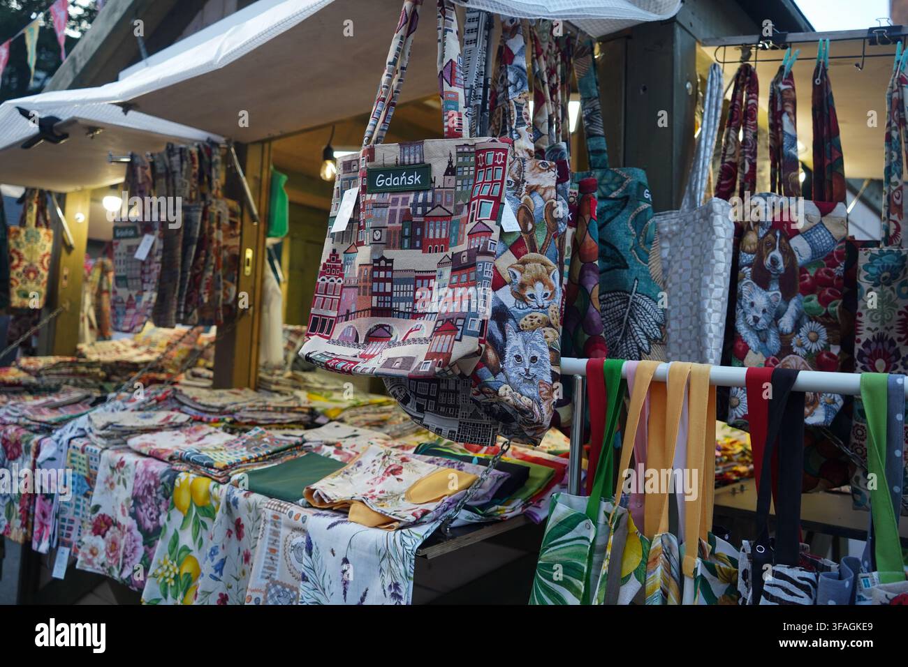 Una bancarella all'aperto che offre borse tote in tappezzeria intrecciata. Una borsa presenta un motivo originale del lungomare della città, dello stemma cittadino e del nome "Gdansk". Foto Stock