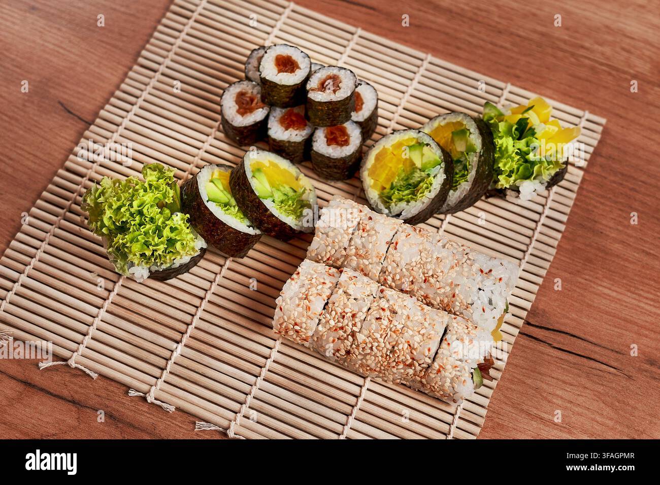 Assortimento di rotoli di sushi vegetariani freschi serviti su un tradizionale tappetino da sushi in bambù. Foto Stock