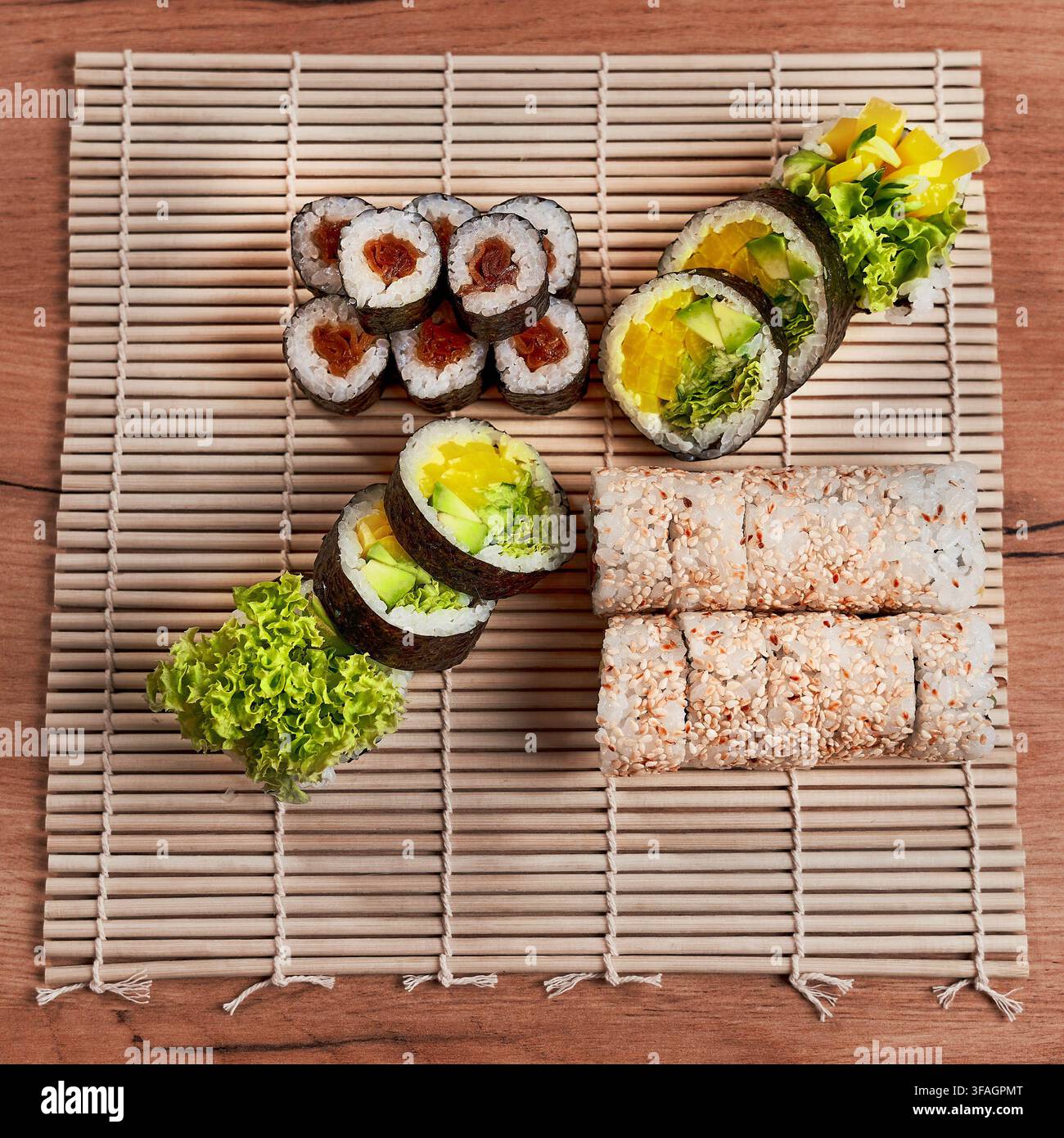 Assortimento di rotoli di sushi vegetariani freschi serviti su un tradizionale tappetino da sushi in bambù. Foto Stock