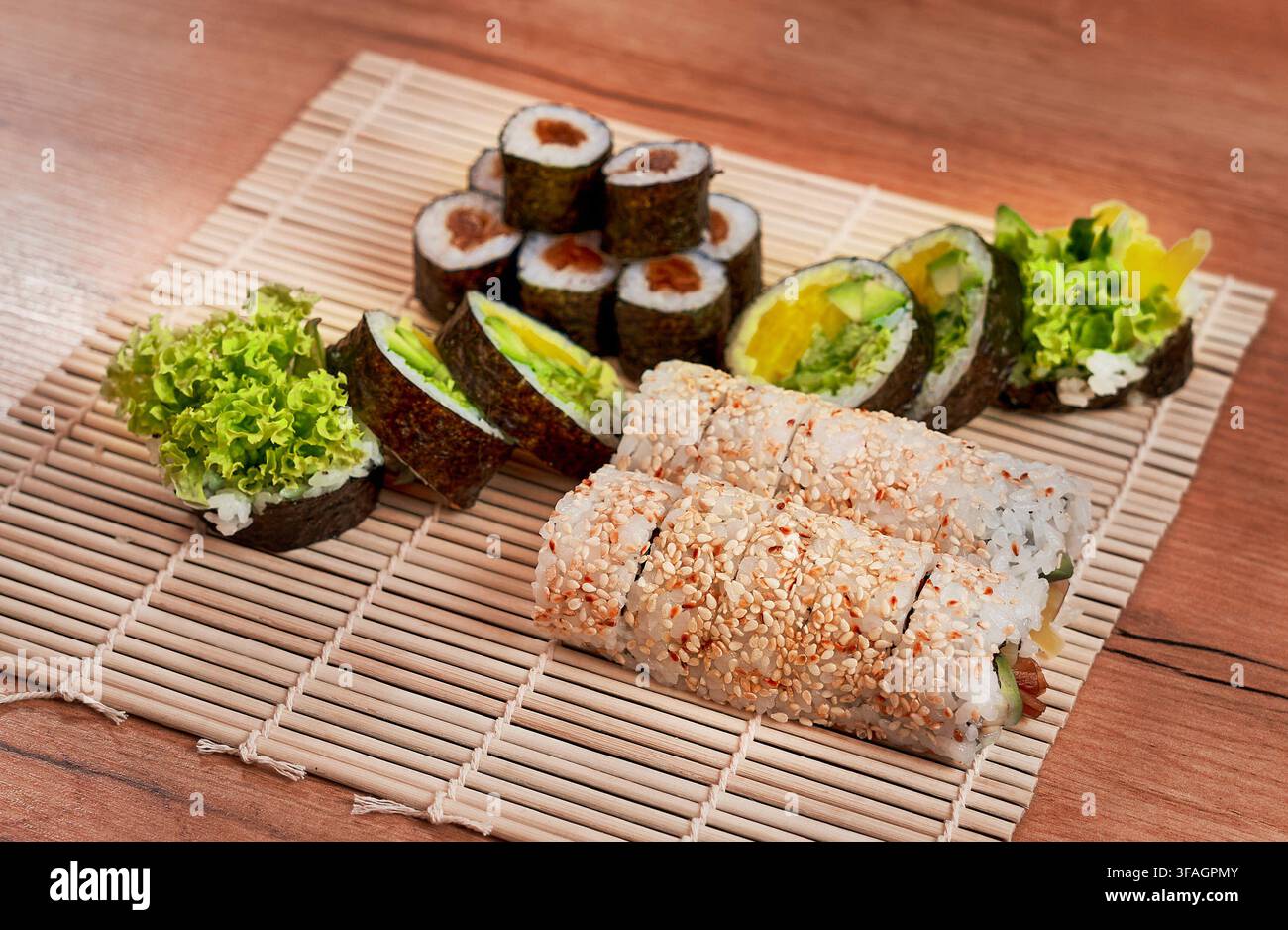 Assortimento di rotoli di sushi vegetariani freschi serviti su un tradizionale tappetino da sushi in bambù. Foto Stock