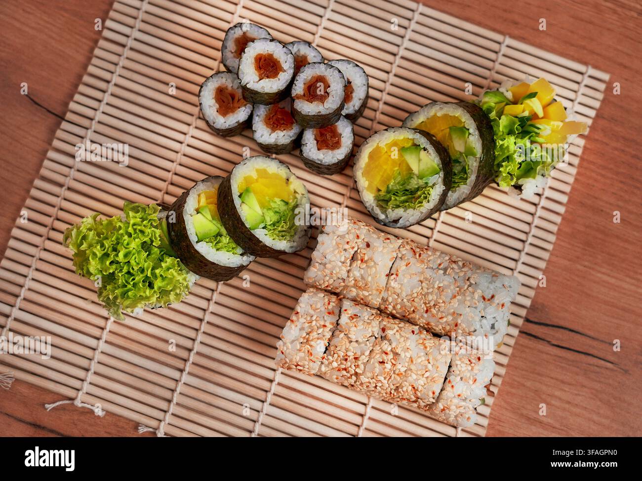 Assortimento di rotoli di sushi vegetariani freschi serviti su un tradizionale tappetino da sushi in bambù. Foto Stock