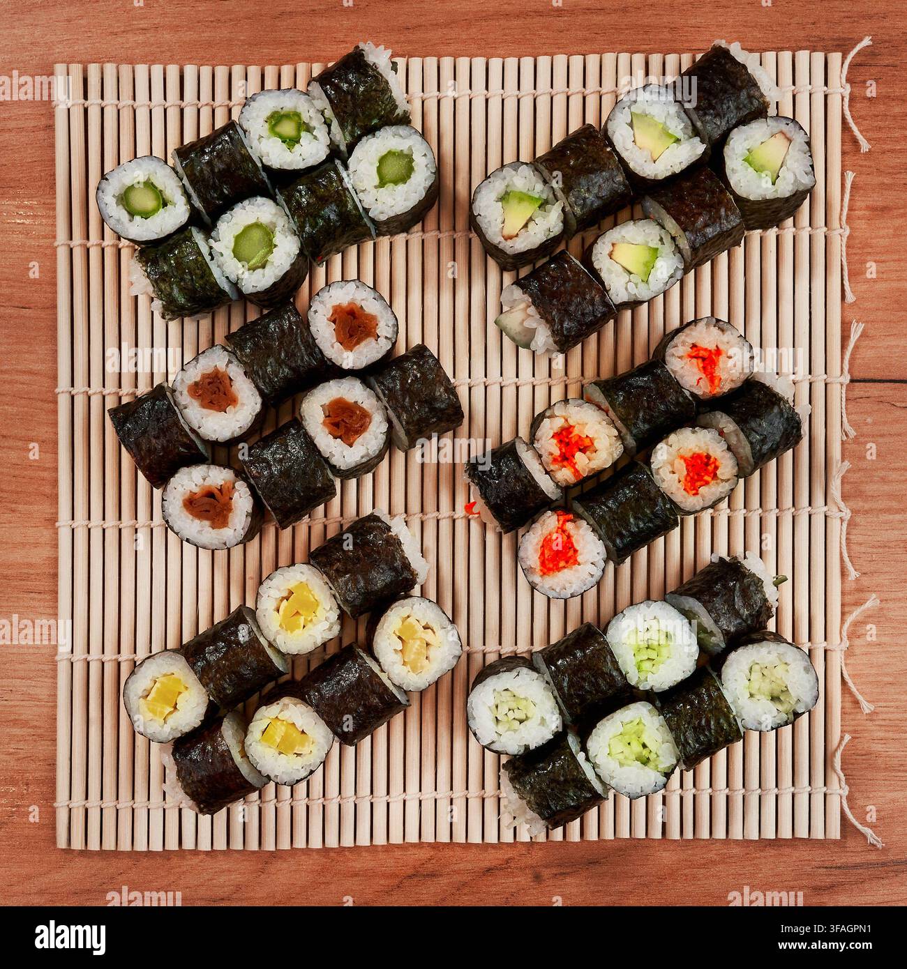 Assortimento di rotoli di sushi vegetariani freschi serviti su un tradizionale tappetino da sushi in bambù. Foto Stock