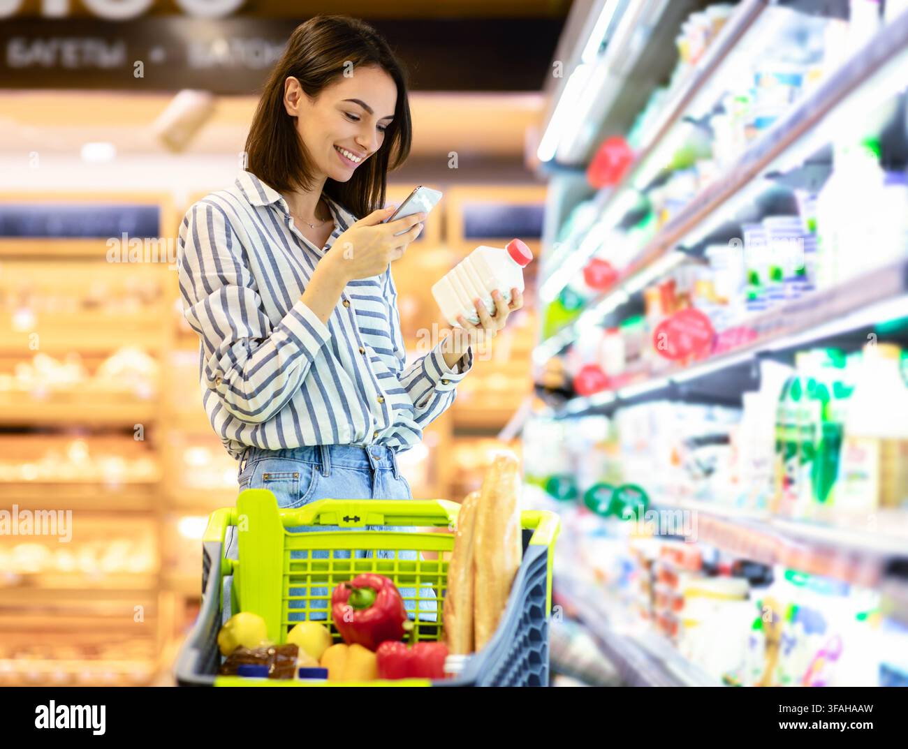Donna che esegue la scansione del codice sui prodotti utilizzando lo smartphone Foto Stock
