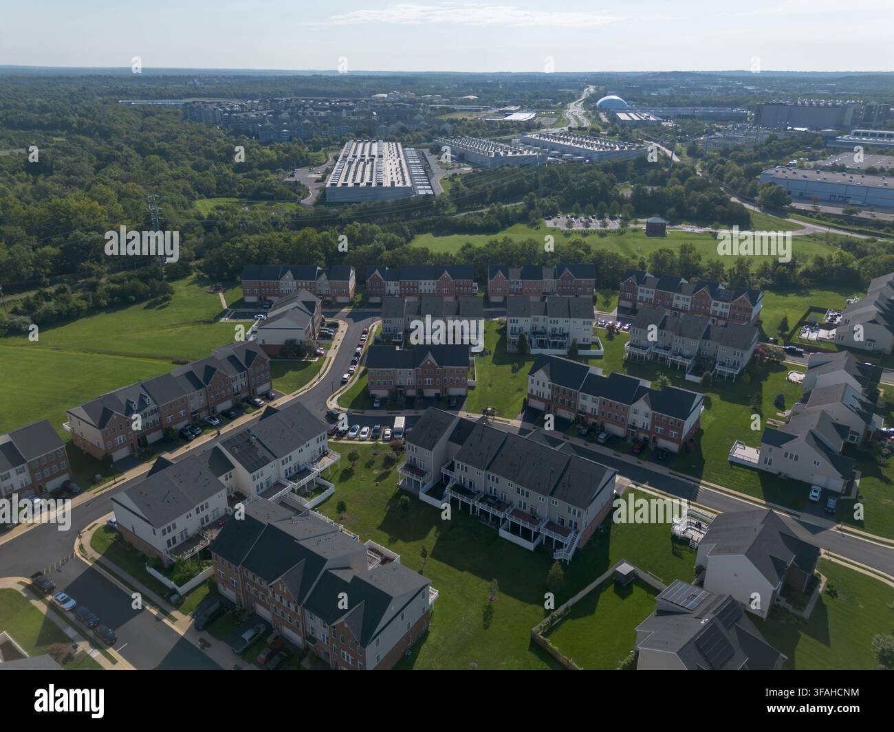 ASHBURN, VIRGINIA, USA - 8 AGOSTO 2026: Vista aerea con drone di ville suburbane vicino a un campus del centro dati di Amazon Web Services nella contea di Loudoun. Foto Stock