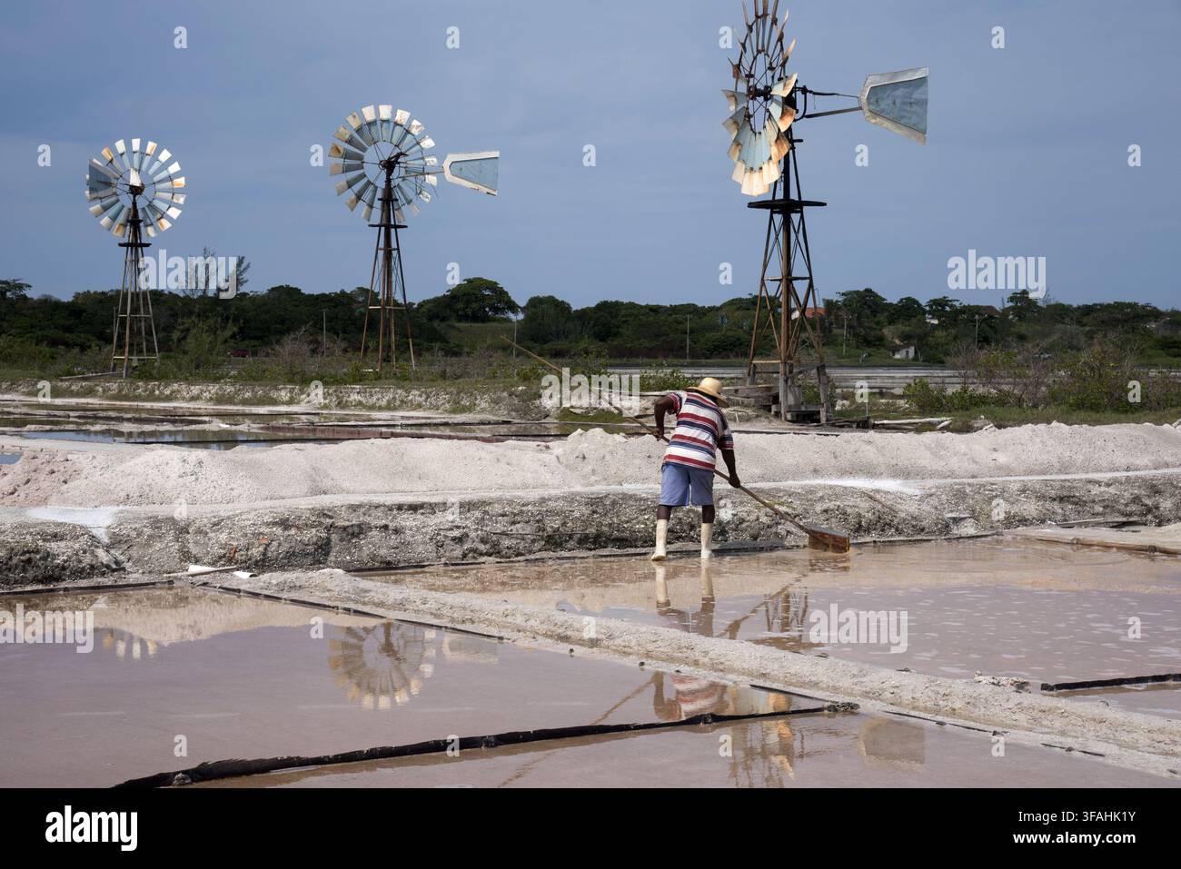 Windsurfer e lavoratore che raccolgono cristalli nelle paludi salate della laguna di Araruama a Praia Seca Foto Stock