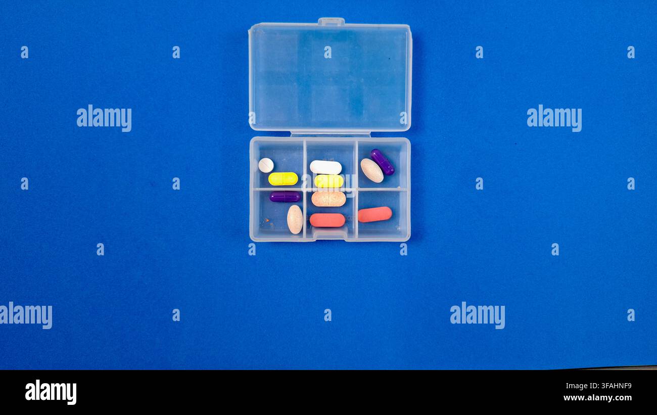 Organizer per pillole con compresse bianche e capsule su sfondo blu Foto Stock