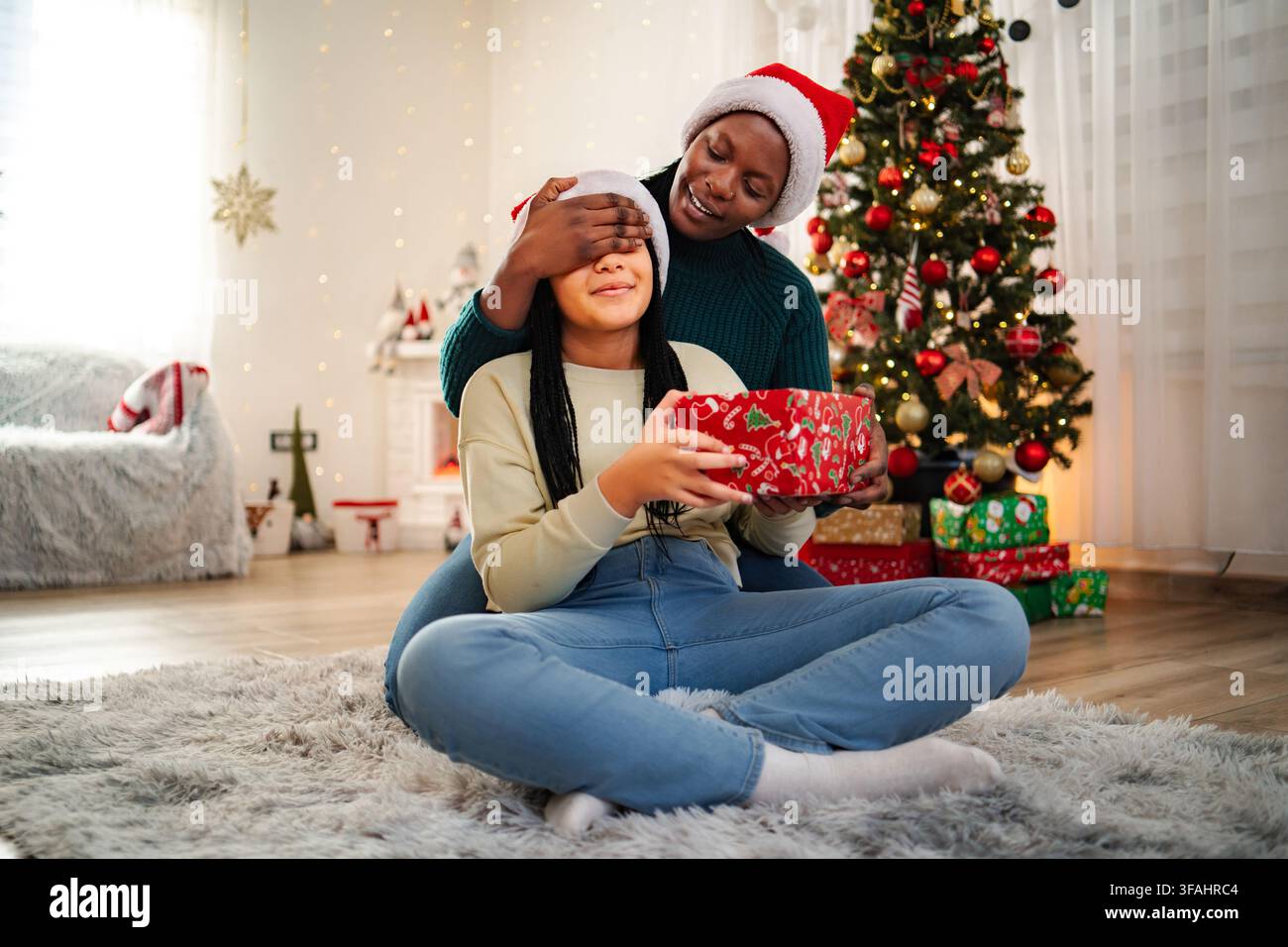 Madre che sorprende la figlia con un regalo di Natale durante le festività Foto Stock