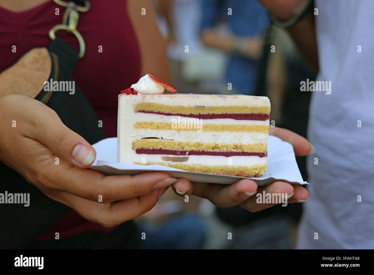 Donna tiene una fetta del dolce dell'anno 2026 dell'Ungheria chiamato Bíborfehér durante la Festa di Santo Stefano (20 agosto) a Budapest, Ungheria Foto Stock