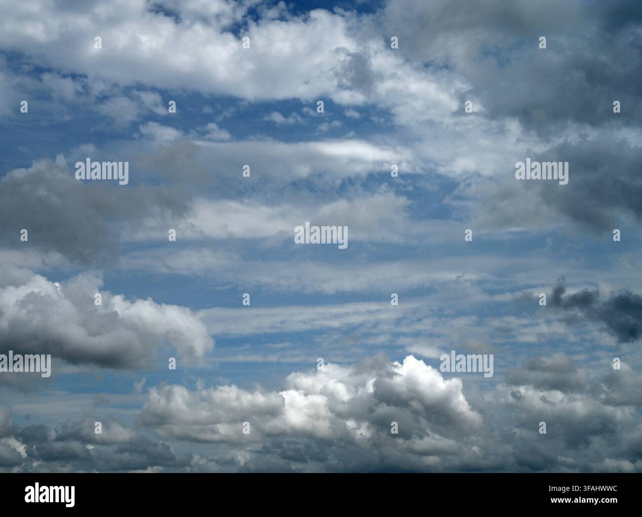 Vista orizzontale di un cielo per lo più nuvoloso con macchie blu e nuvole chiare e scure insieme a nuvole di tono medio Foto Stock