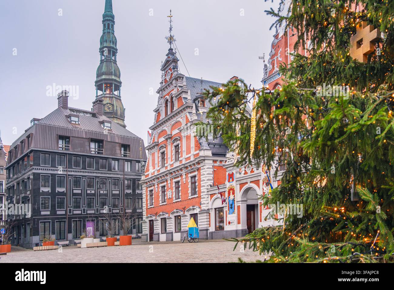 Un'accoglienza festiva storica incornicia la Casa delle Teste Nere e la Chiesa di San Pietro accanto a un albero sempre verde nella Vecchia Città di Riga per il Natale europeo Foto Stock
