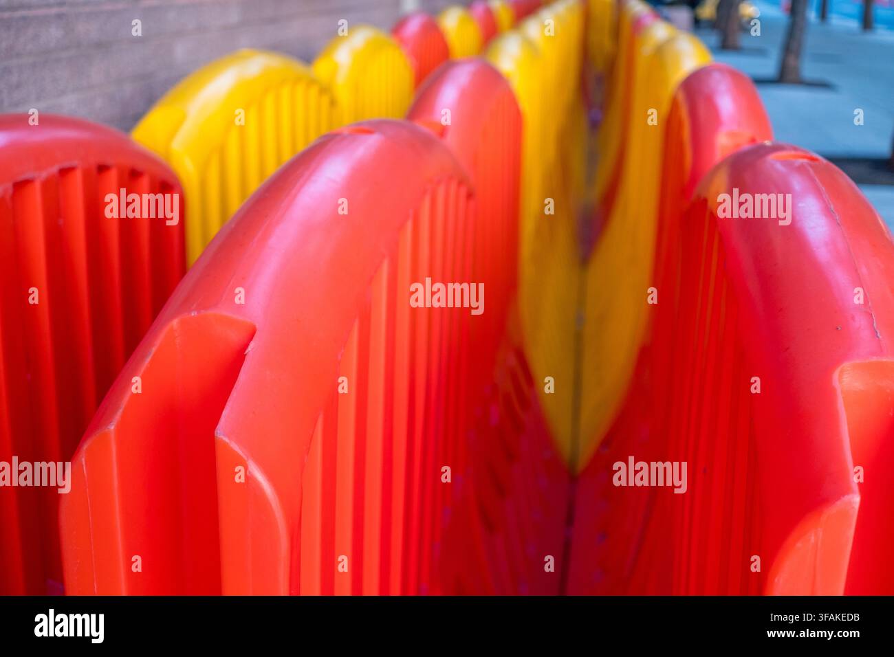 Barriere di plastica dai colori vivaci con texture a costole spesse e sezioni continue rosse e gialle nella strada Foto Stock