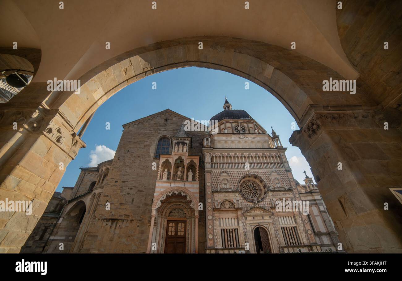 Una vista prospettica suggestiva dal portico del Palazzo della Ragione, che incornicia la cappella rinascimentale Colleoni e la facciata della Basilica Foto Stock