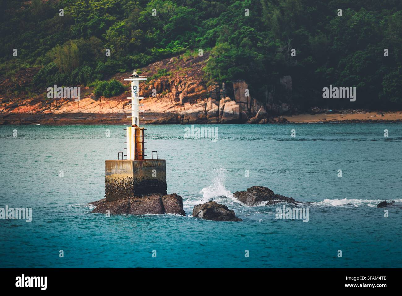 Segnale di navigazione numero 9 in piedi su rocce nel mare con onde che si infrangono contro di esso Foto Stock