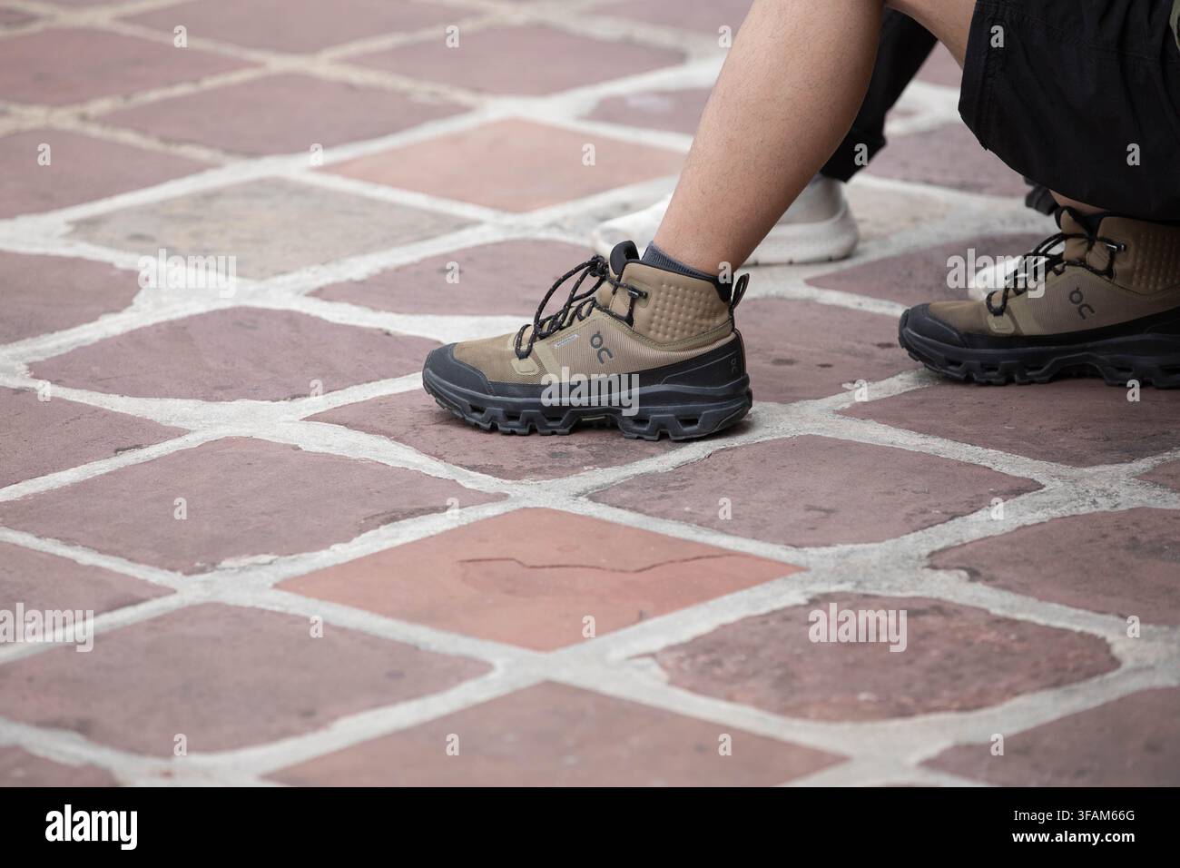 BANGKOK, THAILANDIA - 12 AGOSTO 2026: Uomo con scarpe da ginnastica ON marroni, profilo laterale. Foto Stock