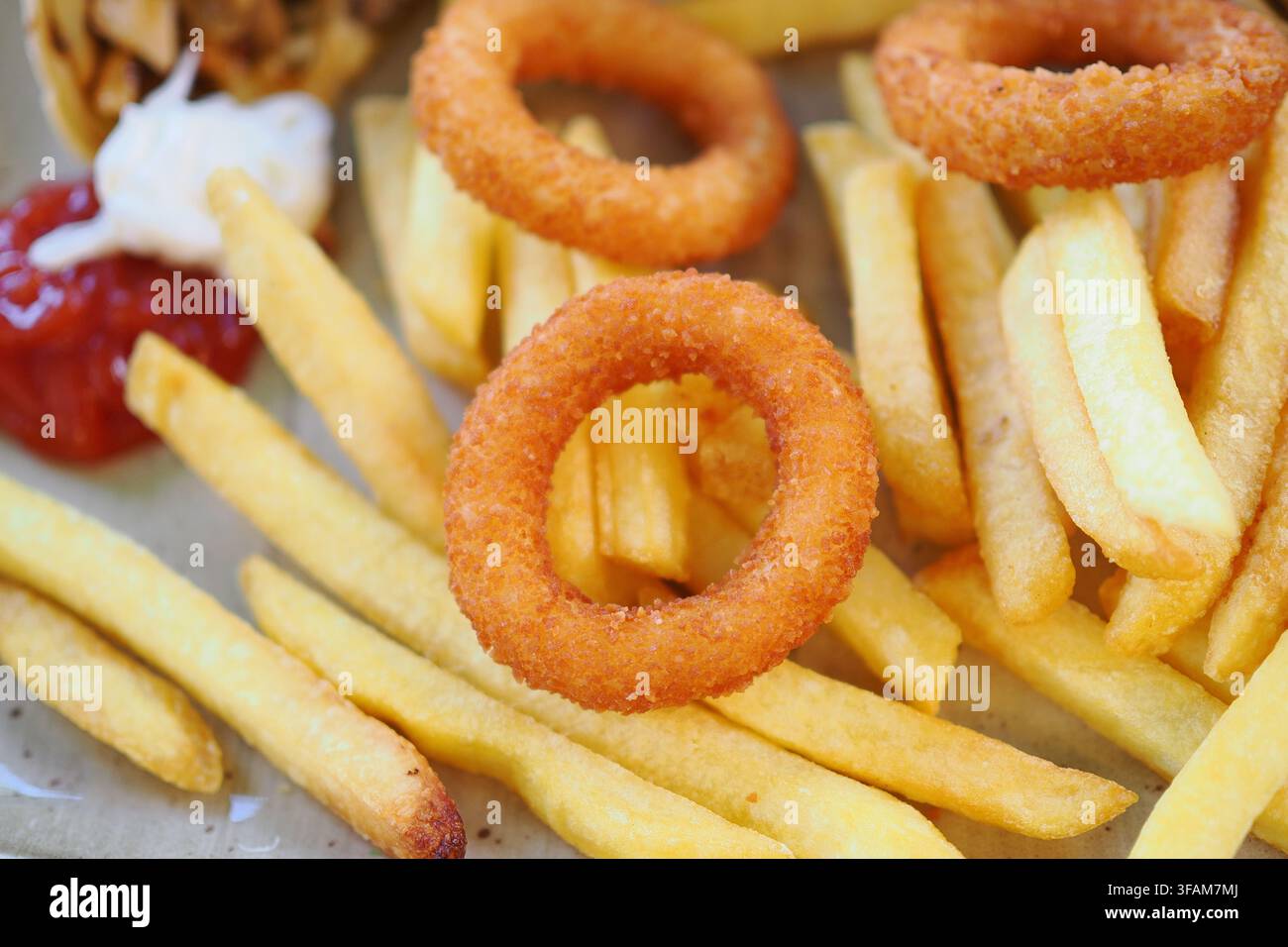 Godersi il cibo con patatine fritte e anelli di cipolla in un ambiente informale Foto Stock