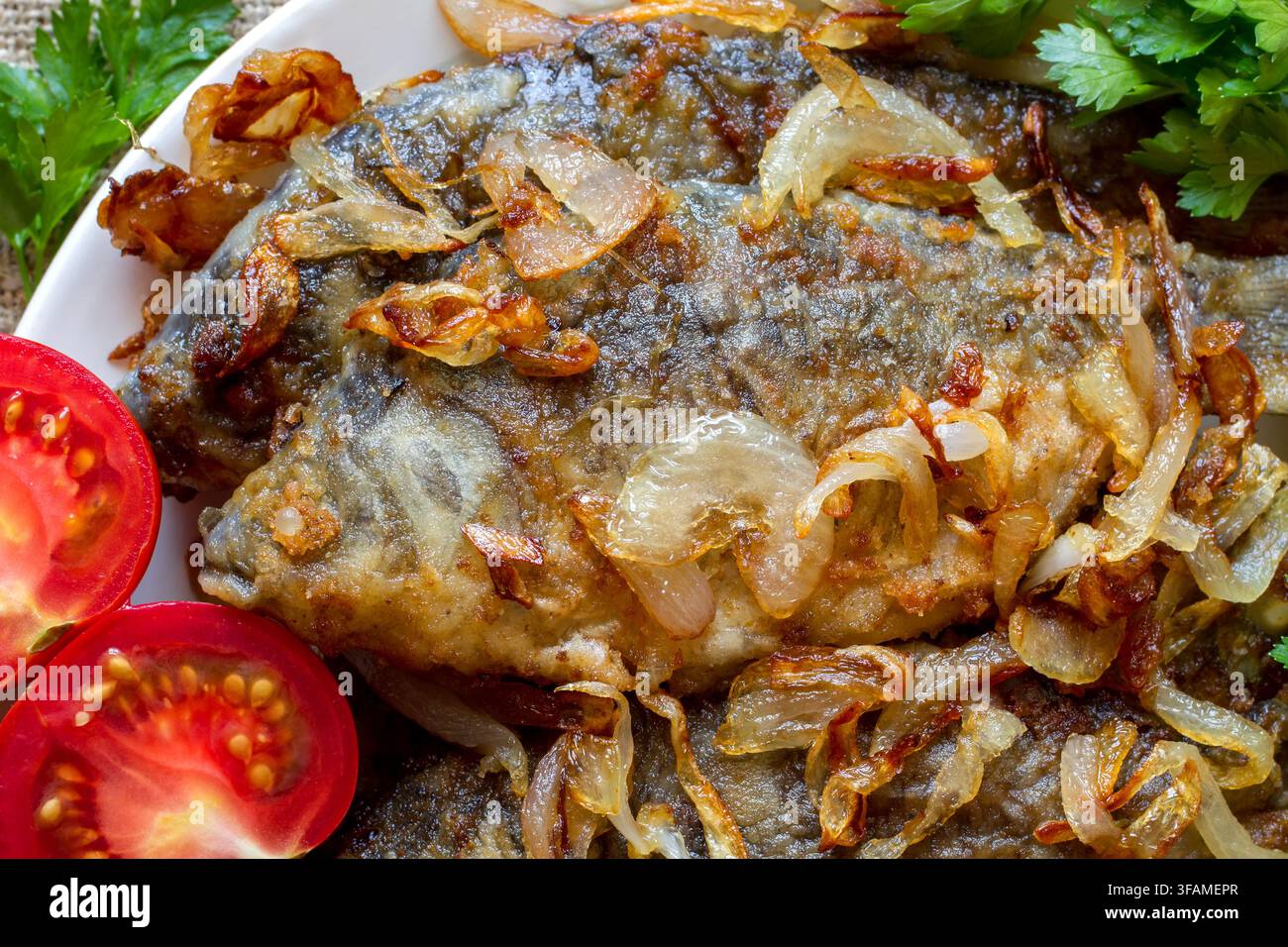 Prima vista di carpa fritta con cipolle. Pesce fresco fritto con verdure Foto Stock