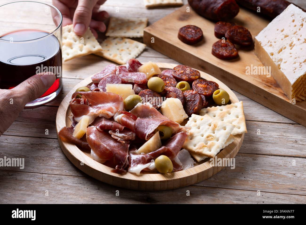 Piatto di tapas spagnole con salumi, formaggio, olive e vino rosso su tavolo di legno Foto Stock
