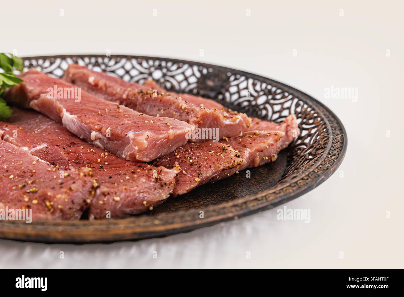 Fette stagionate di carne rossa cruda disposte su un piatto metallico decorativo Foto Stock