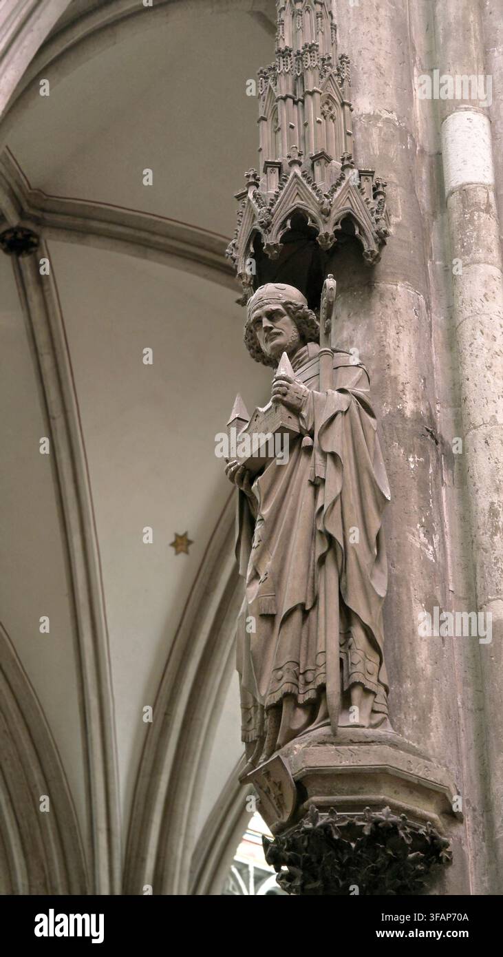 Figura storica in pietra che tiene un modello di edificio tra dettagli architettonici gotici all'interno della cattedrale di Colonia a Colonia, Germania. - Immagine stock catturata con smartphone