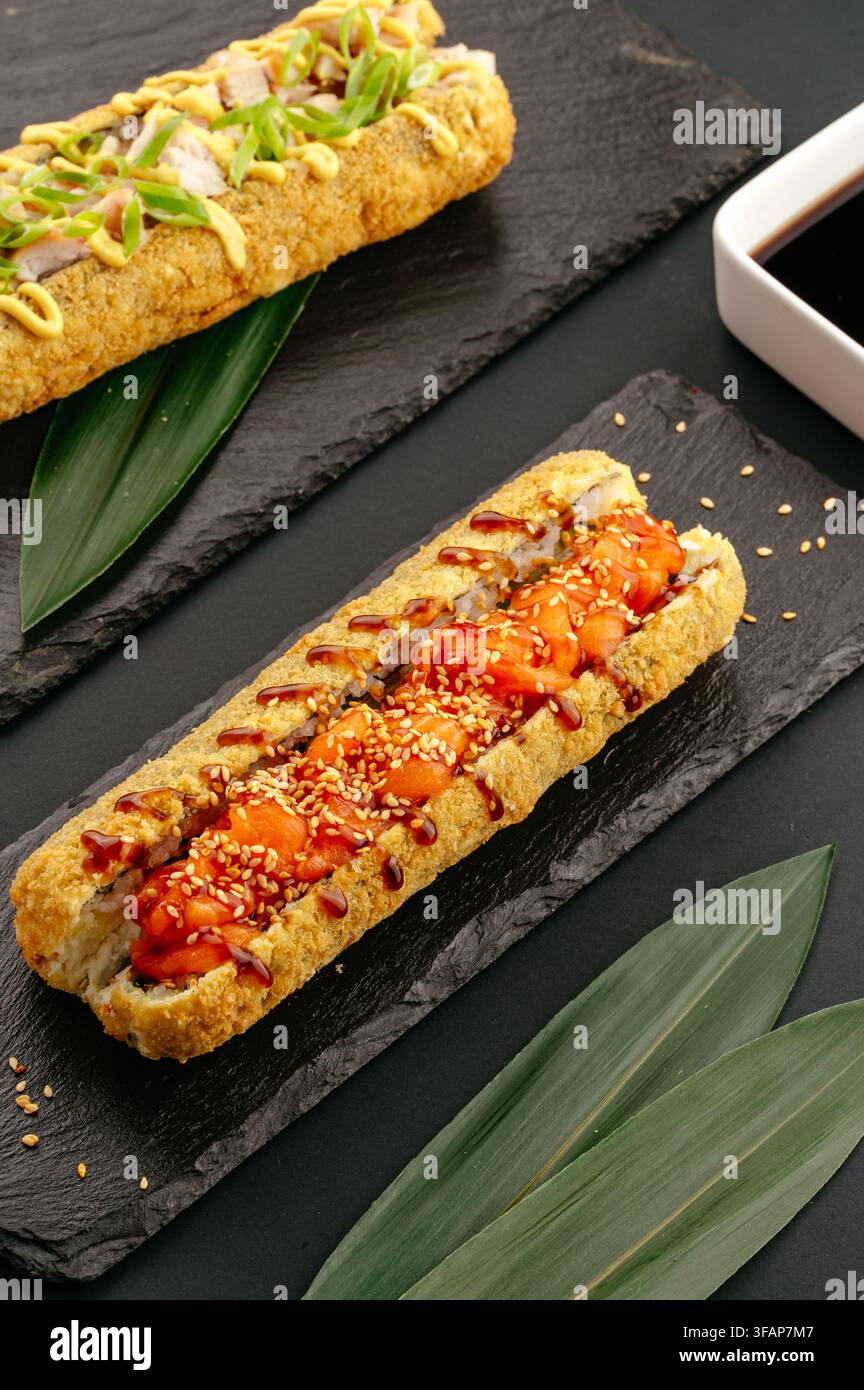 Rotoli di sushi fritti caldi serviti su ardesie nere Foto Stock