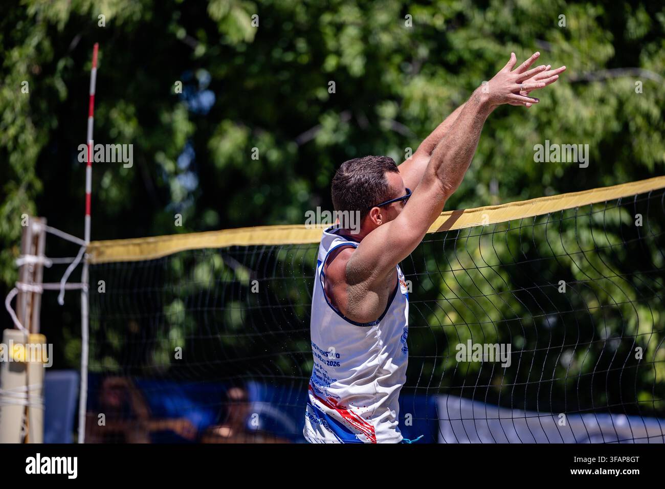 Uomo che serve la palla in una partita di beach volley Foto Stock