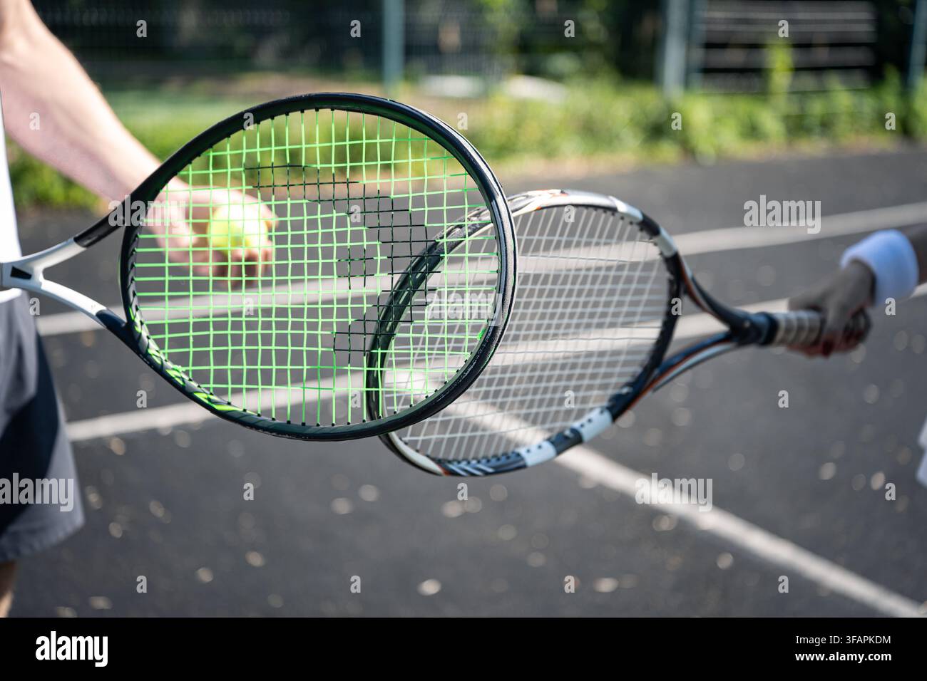 Primo piano di due racchette da tennis che si incontrano su un campo all'aperto, immagine concettuale di competizione, spirito sportivo, partnership e fair play. Foto Stock